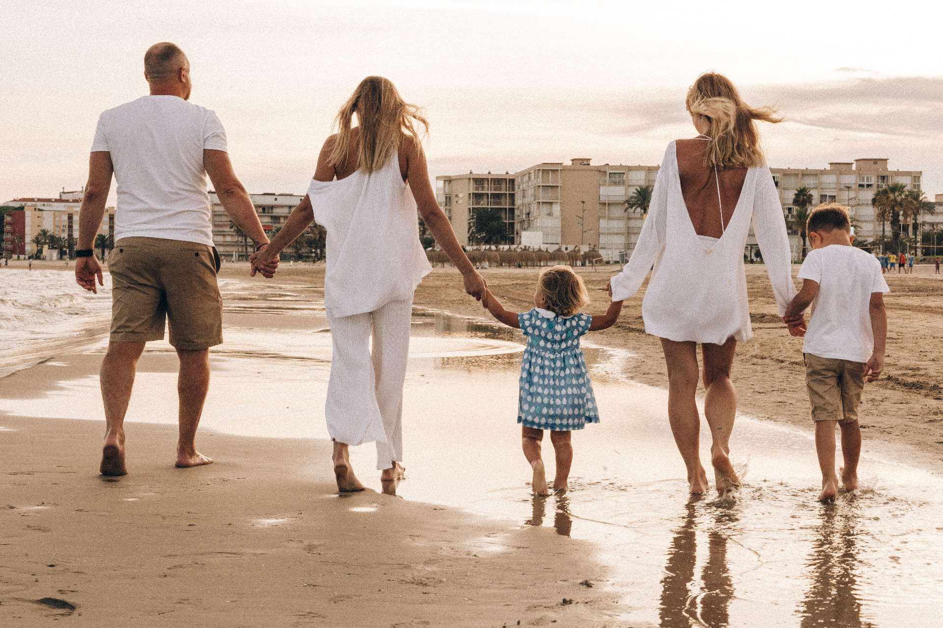 Family walking together on the beach at sunset